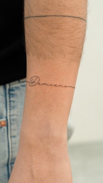 Fine-line name tattoo on forearm