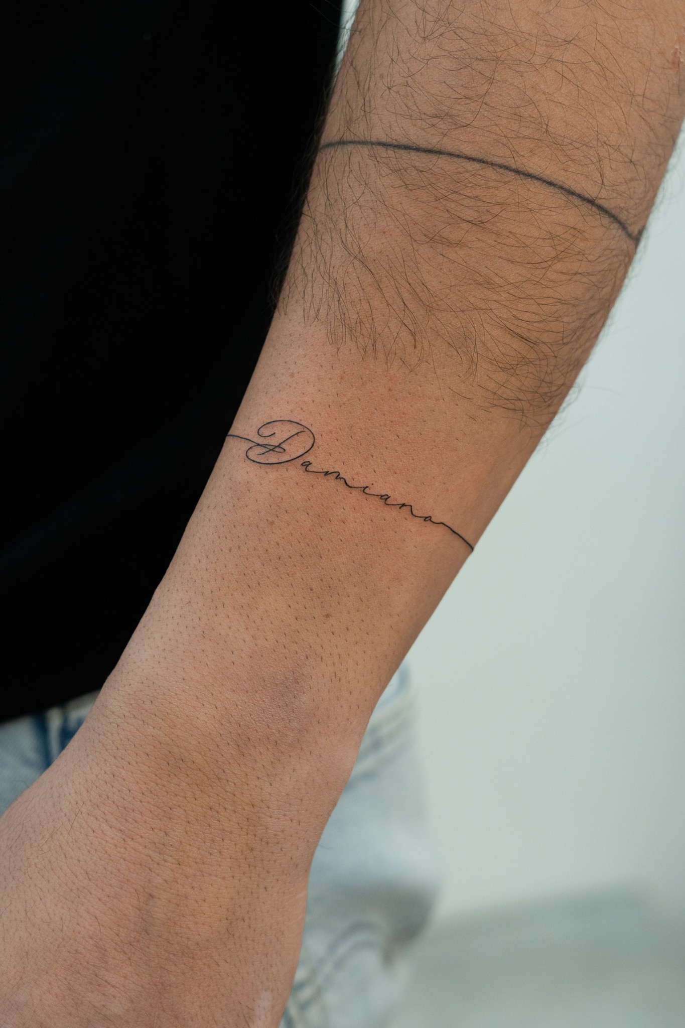 Cursive name tattoo on forearm
