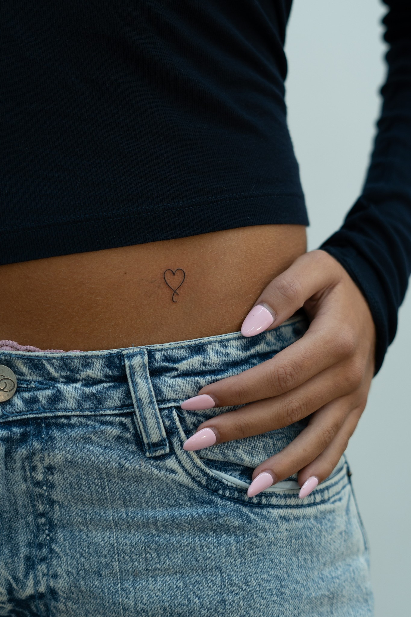 Fine-line heart tattoo on the waist
